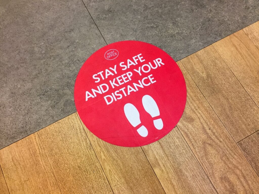 A red floor sticker with the words " stay safe and keep your distance ".