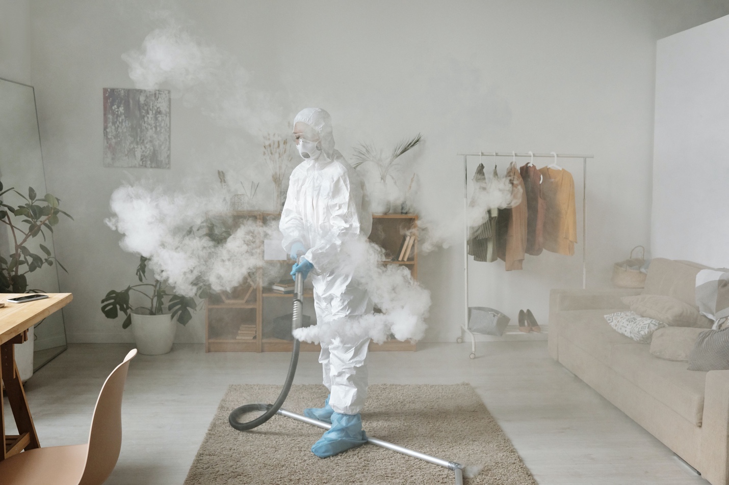 A person in white suit holding a hose