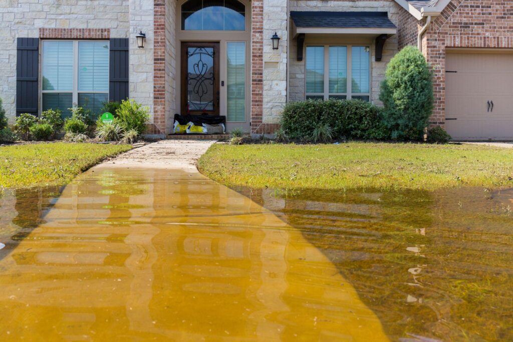 A flooded driveway in front of a house.