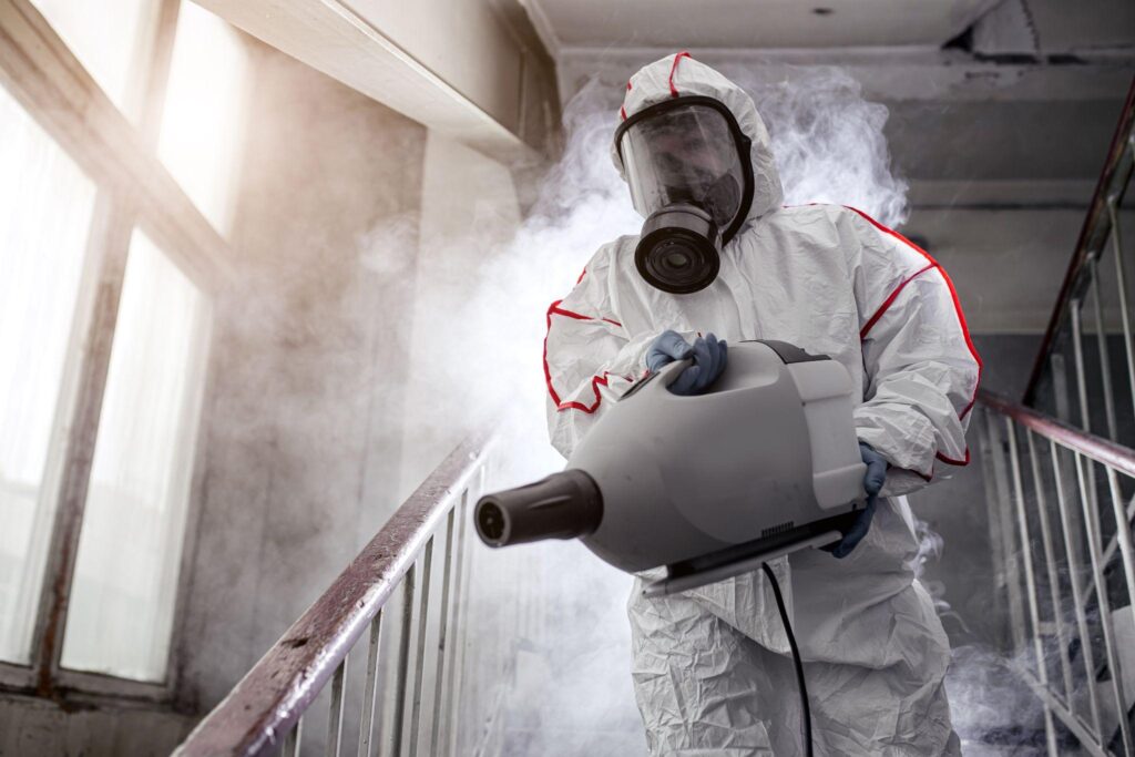 A person in white suit holding a spray gun.