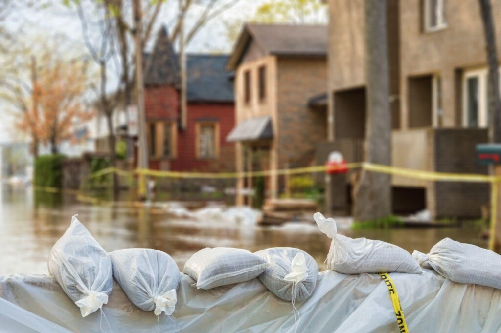 flood Protection Sandbags with flooded homes in the background