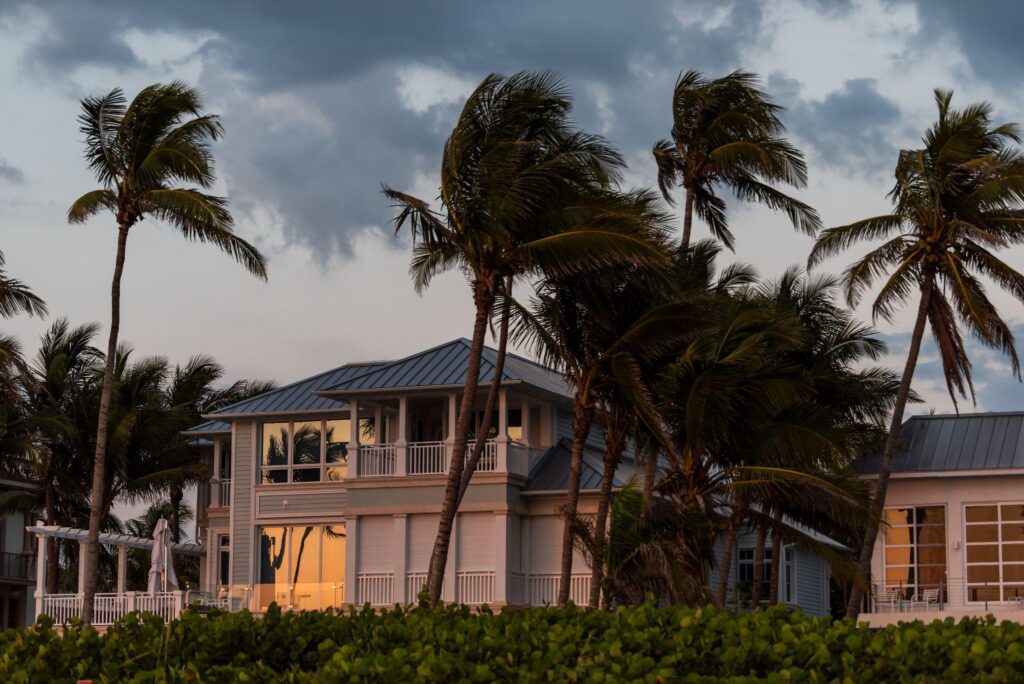 house during evening sunset, storm weather and wind palm trees