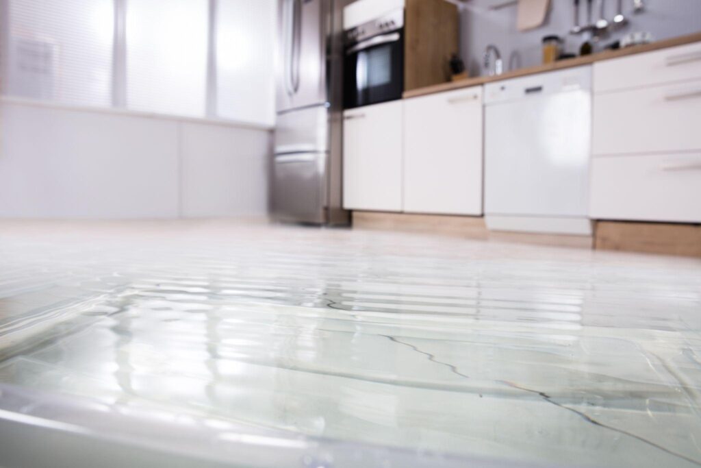 A kitchen with water running down the floor.