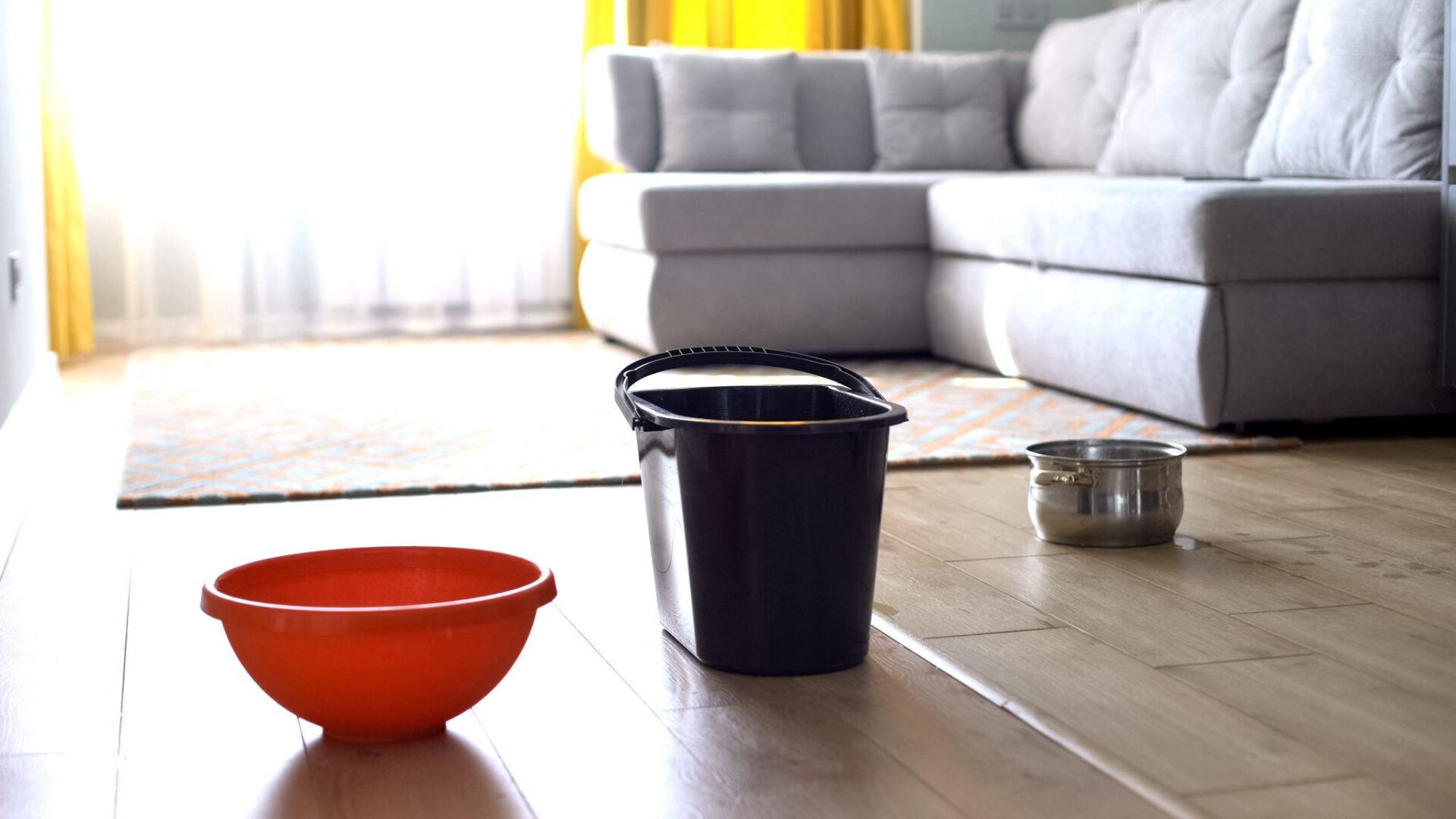 Water dropping in bucket and dishes from ceiling, damaged roof