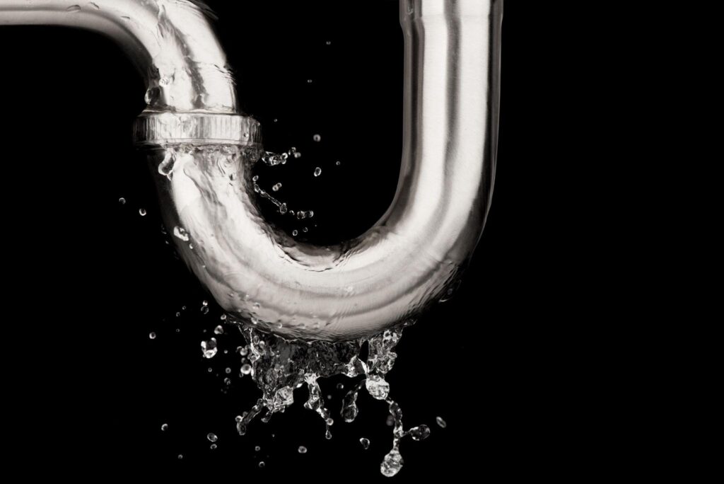 Leaking of water from stainless steel sink pipe isolated on black background