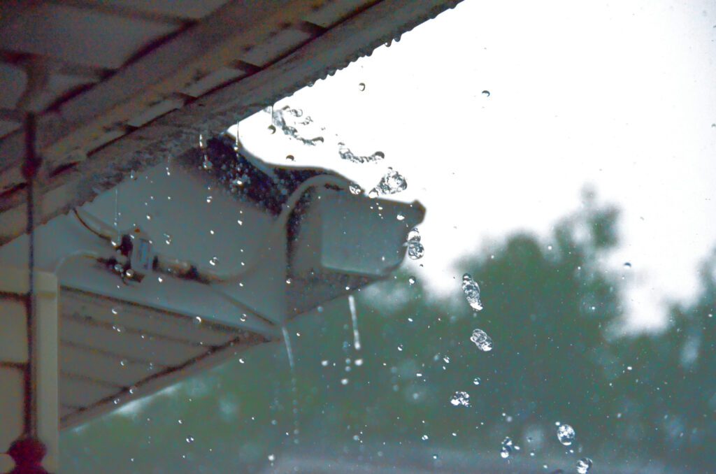 Low angle view of water falling from roof seen through window