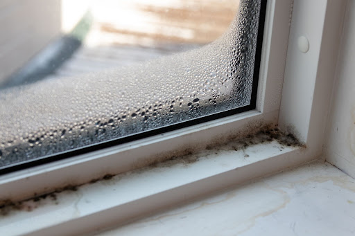 A window with water drops on it and a white frame.