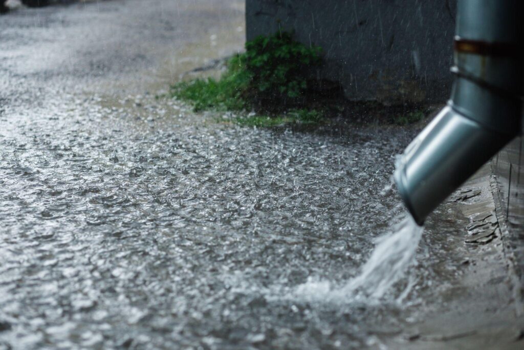 Rain water flowing from a metal downspout during a heavy rain