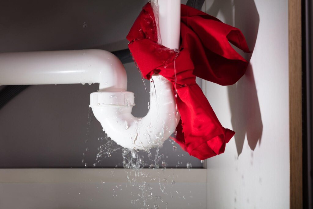 A red bow is hanging from the side of a pipe.