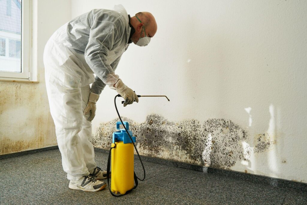 A man in white shirt and gloves holding a spray bottle.